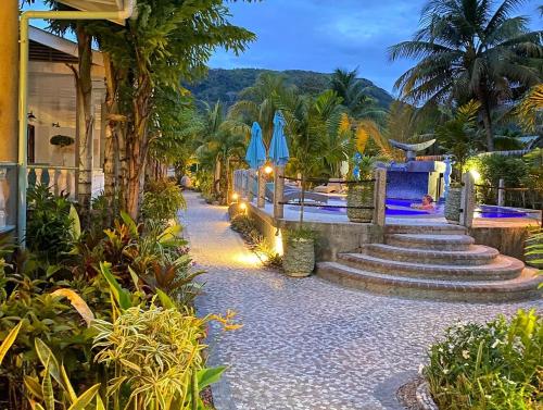 拉迪格岛卡巴内德艾格莉丝酒店的拥有楼梯、蓝色遮阳伞和棕榈树的度假村