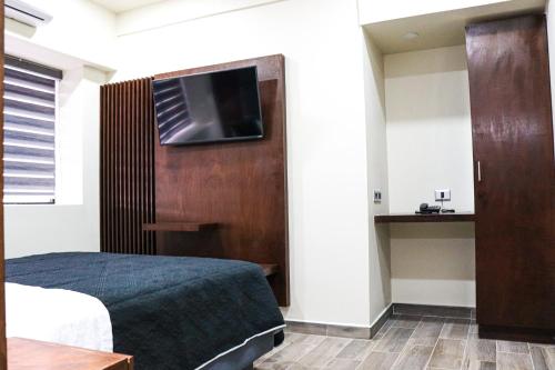 提华纳HOTEL MISION 11的一间卧室配有一张床,墙上配有电视