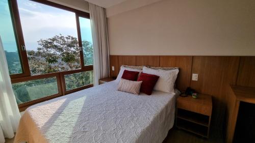 佩德拉阿祖尔Loft 335 Vista Azul的一间卧室配有一张带红色枕头的床和一扇窗户