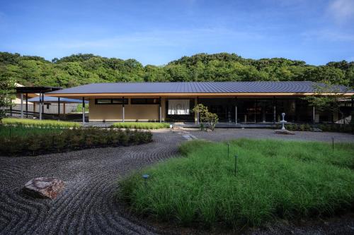 直岛町Naoshima Ryokan Roka的前面有砂石车道的房子