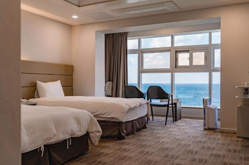 济州市Cocoon Hotel的酒店客房设有两张床和大窗户。
