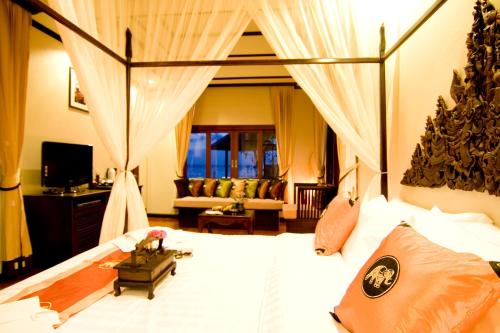 利巴诺伊Kanok Buri Resort的卧室配有带窗帘的大型白色床