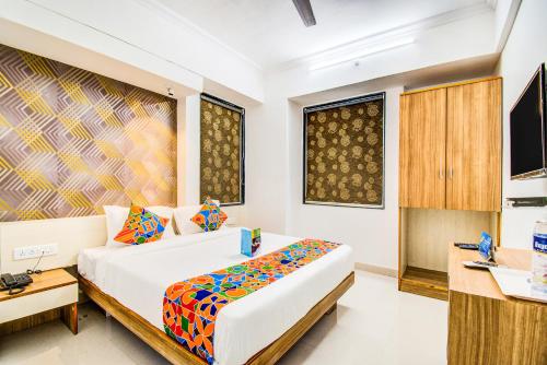 浦那FabExpress Marvel Bliss Viman Nagar的一间卧室配有一张床、一张书桌和一台电视