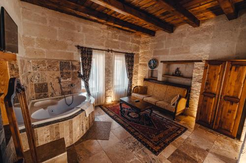 格雷梅Hanzade Cappadocia的一间带大浴缸的浴室,位于一个带沙发的房间