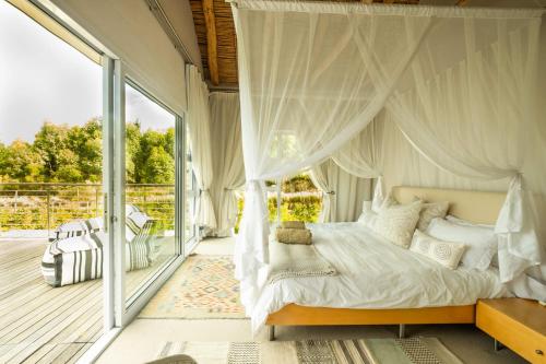 赫曼努斯Stonehaven Eco Cabins的一间卧室设有一张天蓬床和一个阳台