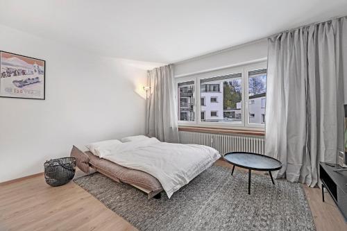 圣莫里茨Abitaziun Belmunt 103 - St Moritz "LOGA ELEGANCE APARTMENT"的一间卧室配有一张床、一张桌子和一个窗户。