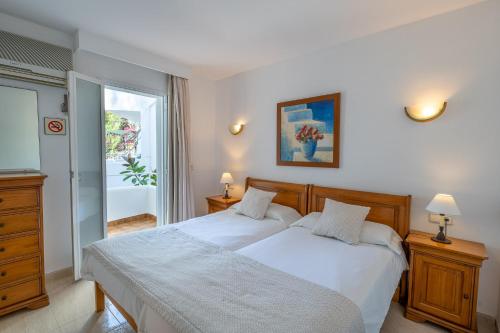 帕格拉Apartamentos Los Tilos的一间卧室配有一张带白色床单的床和一扇窗户。