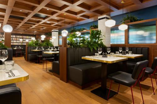 格勒诺布尔RockyPop Grenoble Hotel的一间设有桌椅的餐厅,种植了植物