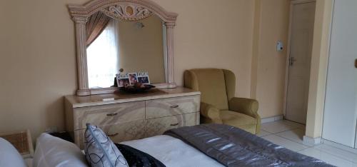 恩潘盖尼Saginix Guesthouse的一间卧室配有镜子、一张沙发和一把椅子