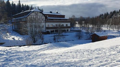 克维尔达Wellness apartmán Pila na Kvildě的雪地里一座大建筑,有雪覆盖的地面