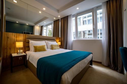 贝尔格莱德马克酒店的一间卧室配有一张带蓝色毯子的大床