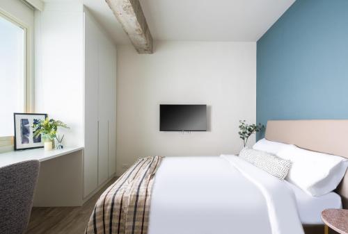 台北Lin Suites by Olala Homes的白色卧室设有一张床和墙上的电视