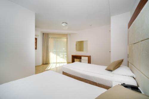 阿拉尼亚Delfino Apart Hotel的白色墙壁客房的两张床