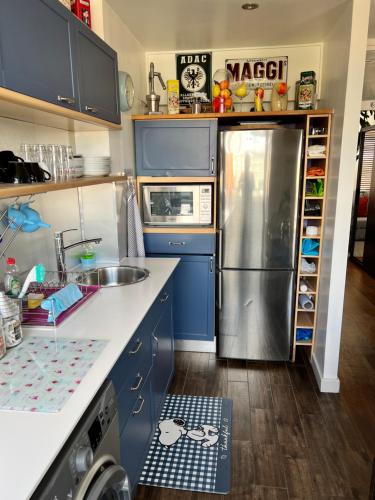 伦敦Prospect House的厨房配有蓝色橱柜和不锈钢冰箱