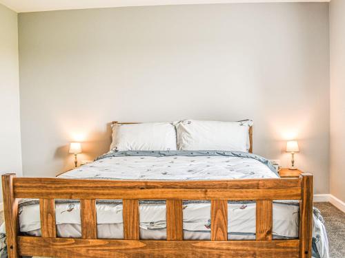 EccleshallSheepfold Cottage的一间卧室配有一张带两盏灯的木床。