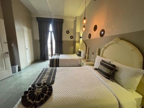 瓦哈卡市Hotel Casona Oaxaca的酒店客房设有两张床和窗户。