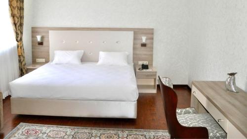 阿特劳Reikartz Sunkar Atyrau的卧室配有白色的床和椅子
