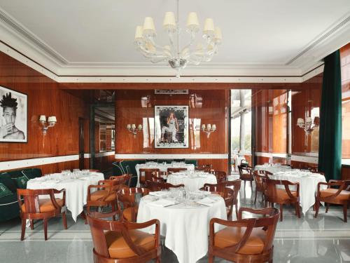米兰Casa Cipriani Milano的餐厅配有白色的桌椅和吊灯