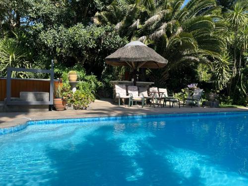 斯泰伦博斯Santika Villa Stellenbosch的一个带桌椅和遮阳伞的游泳池