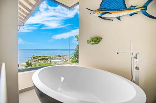 塔卡马卡Paradise Chalets Yoga & Wellness的带浴缸的浴室以及墙上的鱼窗。