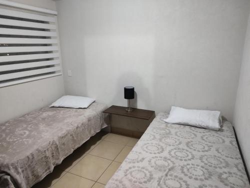 瓜达拉哈拉Excelente Departamento céntrico.的一间卧室设有两张床、床头柜和窗户。