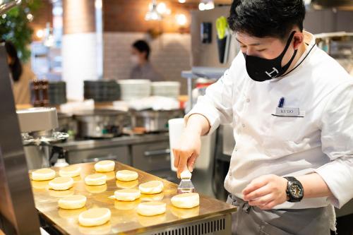 东京DEL style Ikebukuro Higashiguchi by Daiwa Roynet Hotel的厨师在厨房里准备餐桌上的食品