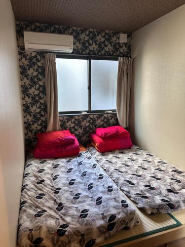 大阪智TOMO的小卧室配有带2个红色枕头的床