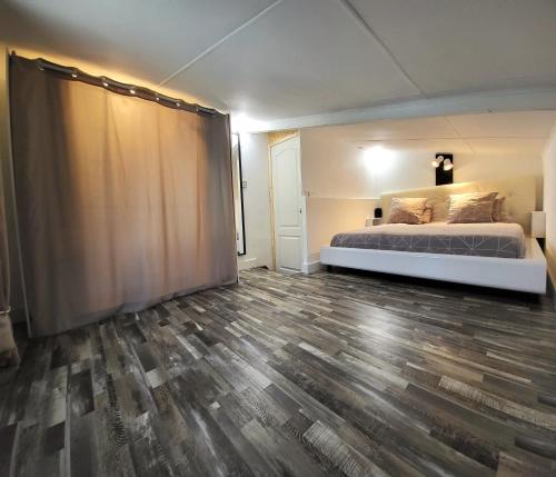 勒唐蓬Tiny House Chaleureuse au Style Contemporain Minimaliste的一间卧室配有一张床,铺有木地板
