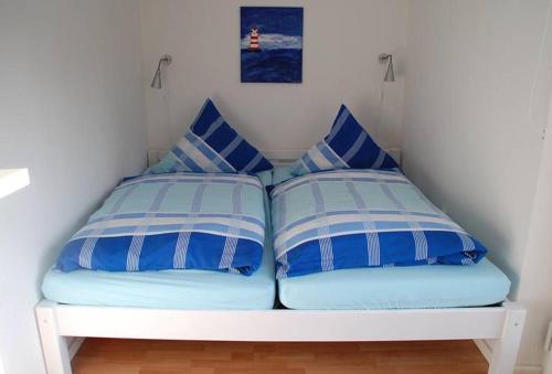 巴德茨维什安Dat Ferienhus的一张带两个蓝色和白色枕头的床