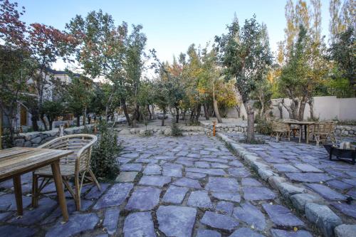 列城Dolkhar Resort的石头庭院设有桌椅和树木