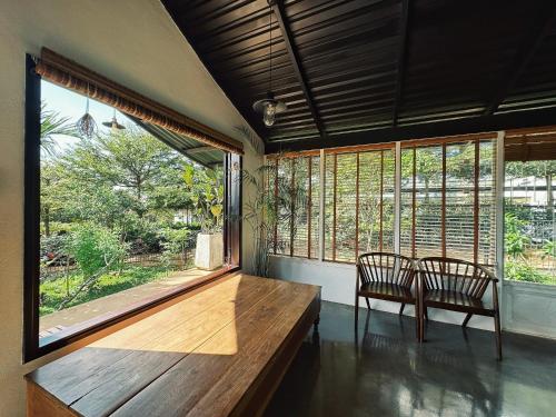 波来古市XOM Organic Farm Stay的一间设有两把椅子和一张木桌及窗户的房间