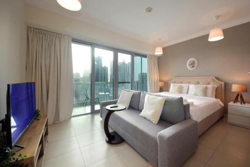 迪拜Prime Retreats- Downtown Dubai的一间卧室配有一张床、一张沙发和一台电视。