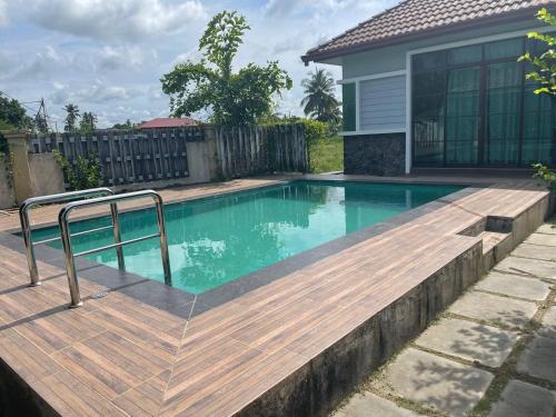 亚娄Alor Lanchang Roomstay的一座带木甲板的游泳池,位于一座房子旁边