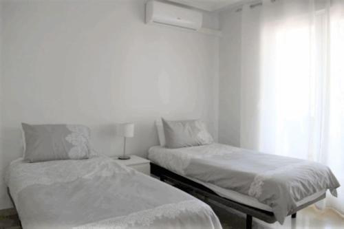 维拉科斯塔Beautiful 2 Bed Apartment on Villamartin Plaza的一间白色卧室,配有两张床和窗户