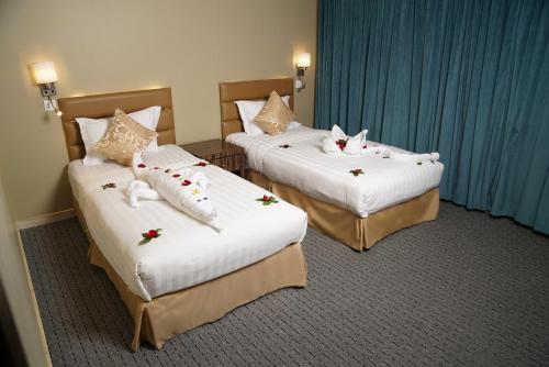 达曼La Rive Hotels & Suites的两张床铺,位于酒店客房内,上面有猫