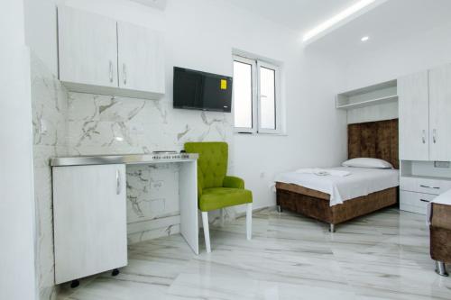 乌尔齐尼Flori Apartments的白色卧室,配有床和绿色椅子