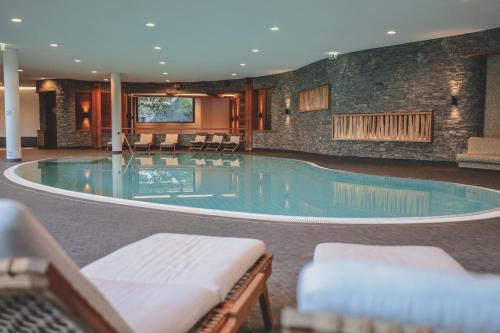 伦策海德普利瓦阿尔派旅馆的大楼内带椅子的大型游泳池