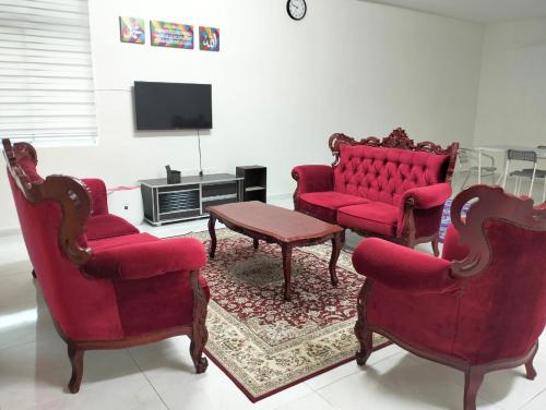 日得拉Mahzan Homestay的客厅配有2把红色椅子和电视