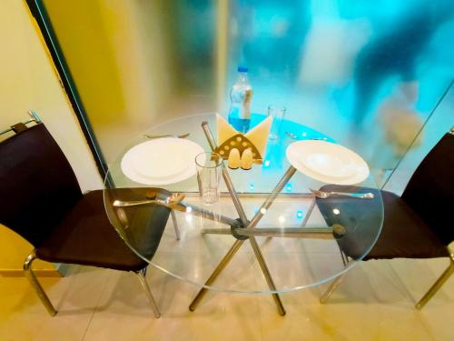 舍地SAI SRUSHTI by NEEM SQUARE的一张玻璃桌,配有两把椅子和一瓶