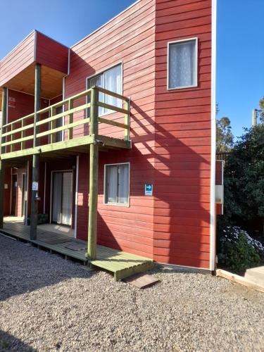 洛斯比洛斯Cabanas Viento Sur. Los Vilos的一座红色的房子,旁边设有楼梯