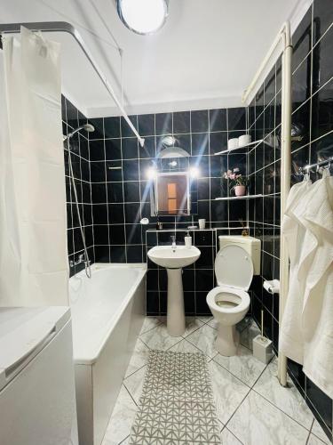 厄尔科Apartament w centrum的黑色瓷砖浴室设有卫生间和水槽