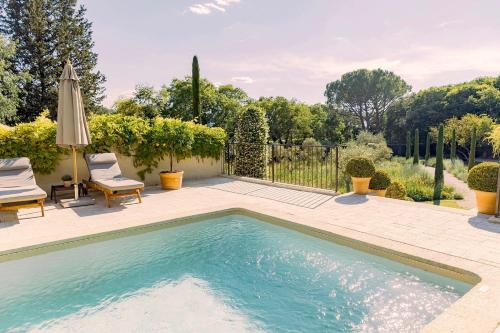 戈尔德Domaine Les Martins - Gordes的庭院内的游泳池,配有两把椅子和一把遮阳伞