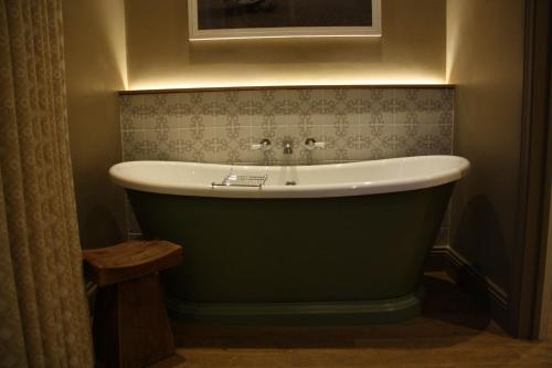 萨克斯曼德姆The Bell Hotel, Saxmundham的客房内的浴室设有绿色浴缸