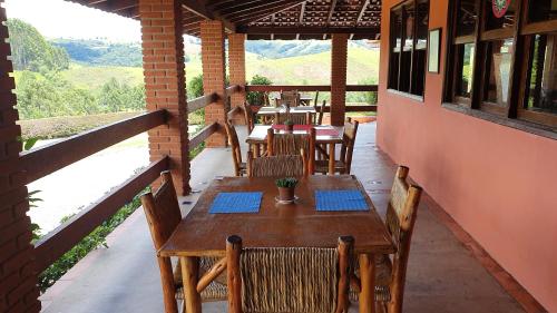 布埃诺布兰当Cachoeira dos Luis - Parque & Pousada的餐厅门廊上的木桌和椅子