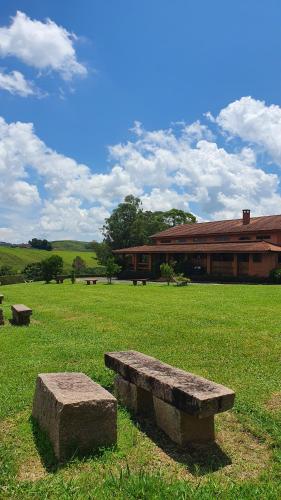 布埃诺布兰当Cachoeira dos Luis - Parque & Pousada的坐在建筑物前方田野上的石凳