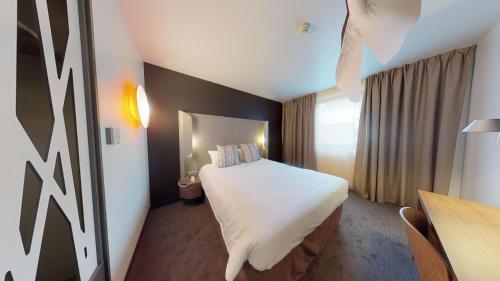 枫丹白露Campanile Fontainebleau的酒店客房设有一张大床和一张书桌。