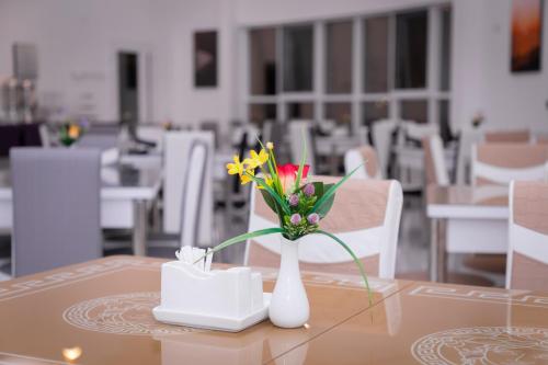 Ghubrat ŢanūfAL shoroq Green Resort的白色花瓶,桌子上放着鲜花