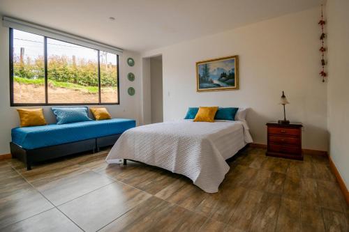 派帕Casa El Roble paipa的一间卧室配有一张床和一张蓝色的沙发