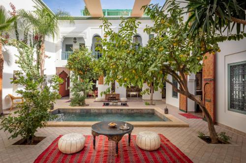 马拉喀什Riad les remparts de la kasbah的庭院设有一座带桌子和树木的游泳池