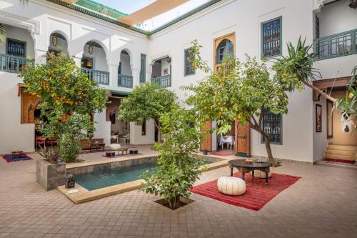马拉喀什Riad les remparts de la kasbah的一座树木繁茂的建筑中,庭院里设有游泳池